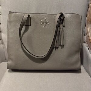 Taupe Tory Burch leather tote bag multiple pockets and hanging strap tassel.